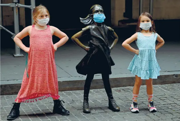  ??  ?? Coraggio Due bambine imitano la posa di «Fearless girl» (la ragazza senza paura), la scultura in bronzo di Kristen Visbal che «sfida» un’altra scultura, il toro di Wall Street, di fronte alla Borsa di New York (foto Johannes Eisele/Afp)