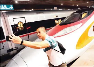  ?? AFP ?? A passenger takes a selfie next to the first train of the Guangzhou-Shenzhen-Hong Kong Express Rail Link after it arrived in Shenzhen on Sunday.