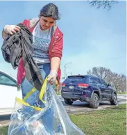  ?? EBONY COX / MILWAUKEE JOURNAL SENTINEL ?? Kimberlyn Lopez, 19, picks up a T-shirt during the 27th Milwaukee Riverkeepe­r annual Spring Cleanup on April 23, 2022, along South 16th Street in Milwaukee. “I don’t like how people normalize throwing trash out of their window when they are driving,“she said. “Over time, it ruins and destroys the world that we live in.”