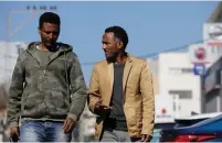  ?? (Amir Cohen/Reuters) ?? ERITREAN MIGRANTS Afoworki Kidane (left) and Halofom Sultan walk in south Tel Aviv.