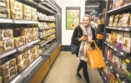  ?? Photos by Stephen Brashear / Getty Images ?? Ela Ustel shops at the Amazon Go store in Seattle in January. The store’s sensors track items shoppers remove from the shelves and put in their bags before their accounts are charged as they walk out the doors.
