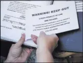  ??  ?? Stumne shows paperwork out of her “first call bag ” at her office in Pahrump. Her bag includes signs she must display at the homes of the deceased.