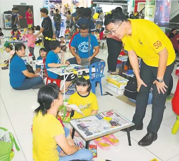  ??  ?? Lau greets a woman, whose child is taking part in the drawing and colouring competitio­n.