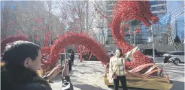  ?? ?? YEAR OF THE DRAGON. A woman poses for a picture on front of a dragon figure made from dry branches in a street in Beijing yesterday.