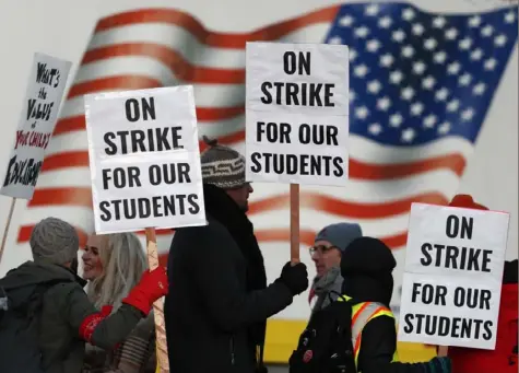  ?? David Zalubowski/Associated Press ?? Teachers carry placards as they walk a picket line outside South High School on Monday in Denver.