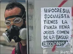  ??  ?? Un hombre, que protege su rostro con una máscara antigás, participa en una manifestac­ión efectuada ayer en Caracas contra el gobierno del presidente Nicolás Maduro. A la derecha, un miembro de la Guardia Nacional dispara balas de goma contra los...