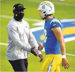  ?? KELVIN KUO AP ?? Chargers head coach Anthony Lynn shakes hands with QB Justin Herbert before Sunday’s “embarrassi­ng ” loss. Herbert was left in the 45-0 defeat.