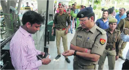  ?? Deepak Gupta / Getty Images ?? A policeman checks the identity card of a man at a mall in Lucknow, part of efforts to deter men from pestering women.