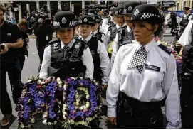  ?? MARKUS SCHREIBER / ASSOCIATED PRESS ?? Police officers bear flowers Wednesday to lay at the scene of Saturday’s terrorist attack in London. Revelation­s about the three attackers have placed Prime Minister Theresa May under scrutiny in advance of today’s election.