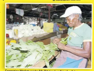  ??  ?? Coronation Market vendor Ms Pat ties bundles of callaloo.