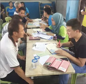  ??  ?? Volunteers help to take down details of dog owners before they are sent to the next station.