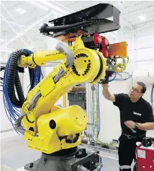  ??  ?? Machine builder George Granada works with an automotive parts robot during the grand opening of Reko Automation Division in Lakeshore on Monday.