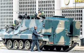  ?? GETTY IMAGES ?? A man walks past a military tank parked on the side of a street in the Zimbabwean capital, Harare, on Thursday, a day after the military took power and placed 93-year-old President Robert Mugabe under house arrest.