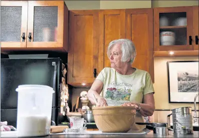  ?? AP PHOTO ?? Anne Hunt looks to her husband, Bruce, to be reminded if she already added sugar or not to her dough in their home in Chicago on July 13. Diagnosed with Alzheimer’s in 2016, Anne, who once ran a Chicago cooking school, now has to separate the ingredient­s and mixing to two different sections of the kitchen to prevent any errors.