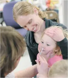  ??  ?? Chelsea Erickson holds her two year-old daughter Charlotte while she receives a flu mist vaccinatio­n Thursday.