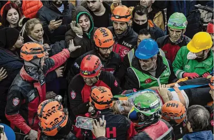  ?? Petros Giannakour­is/Associated Press ?? Raziye Kilinc is carried through a crowd Friday after she was rescued under a building as her daughter, center with the hood, waves in Iskenderun, Turkey. A married couple also was pulled from the rubble after spending 109 hours buried.