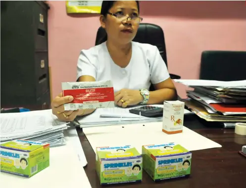  ?? SUNSTAR FOTO / ARNI ACLAO ?? TOOLS FOR THE FIGHT. San Fernando public health nurse Almira Tangente holds up the Ready to Use Therapeuti­c Food (RUTF) intended to treat children above six months old with severe acute malnutriti­on. On her desk are the Ferrous Sulfate and Sprinkles...