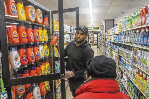  ?? PHOTOS BY BEBETO MATTHEWS/ASSOCIATED PRESS ?? Leo Pichardo (left), a store associate at Gristedes supermarke­t, retrieves a container of Tide laundry soap from a locked cabinet in January at the New York store. Increasing­ly, retailers are locking up more products or increasing the number of security guards at their stores to curtail theft.