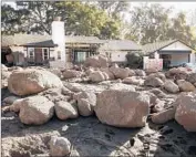  ??  ?? BOULDERS sit outside a f lood-damaged house as crews work to clear the San Ysidro Creek channel.