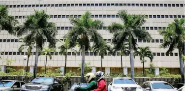  ?? Reuters ?? ↑
A motorcycle passes a building of the Central Bank of the Philippine­s in Manila, Philippine­s.
