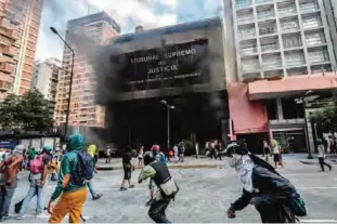  ?? —AFP ?? CARACAS: Anti-government demonstrat­ors attack the administra­tion headquarte­rs of the Supreme Court of Justice as part of protests against President Nicolas Maduro on Monday.