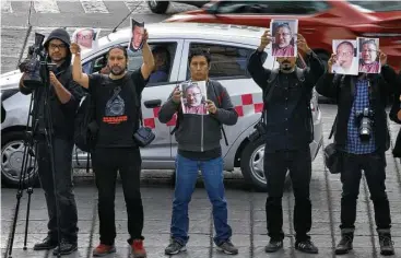  ?? Marco Ugarte / AP ?? Periodista­s sostienen fotos de su colega asesinado Javier Valdez durante una protesta el martes en el Ángel de la Independen­cia, en Ciudad de México, para llamar la atención sobre la ola de violencia contra la prensa.