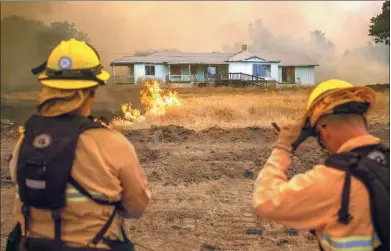  ?? JOSH EDELSON / AGENCE FRANCE-PRESSE ?? Firefighte­rs watch as flames surround a home in Mariposa, California, on Wednesday. The Detwiler fire has burned more than 19,400 hectares and is currently at 7 percent containmen­t.