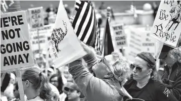  ?? Associated Press ?? ■ In this April 25 photo, Dave Fitzgerald of Girard, Ill., waves flags while listening to speakers during the annual Illinois Gun Owners Lobby Day rally at the Capitol 8 in Springfiel­d, Ill. A growing number of rural counties in Illinois are standing...