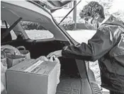  ?? JACQUELYN MARTIN/AP ?? Georgetown Day School junior Will Olsen places bags holding components of medical face shields into a vehicle.