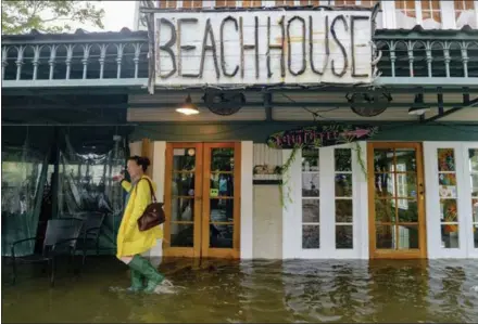  ?? MATTHEW HINTON — THE ASSOCIATED PRESS ?? Aimee Cutter, the owner of the Beach House restaurant, walks through a storm surge from Lake Pontchartr­ain on Lakeshore Drive in Mandeville, La., ahead of Tropical Storm Barry on Saturday.