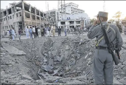  ?? RAHMAT GUL / ASSOCIATED PRESS ?? Security forces stand next to a crater created by a massive explosion Wednesday in front of the German Embassy in Kabul, Afghanista­n. The suicide truck bomb hit a highly secure diplomatic area of Kabul, killing at least 80 people and wounding 400 more.