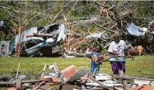  ?? Sean Rayford / Getty Images ?? People clean up storm debris Monday near Nixville, S.C. Scientists are studying whether two EF3 tornadoes that hit the Palmetto State combined.