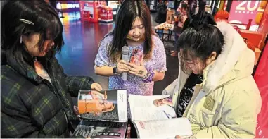  ?? — afp ?? young fans reading a lyrics book of singer Taylor swift before watching the concert film ‘Taylor swift: The eras Tour’ at a cinema in Beijing.