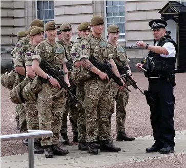  ??  ?? Joint operation: A police officer directs troops deployed at Buckingham Palace