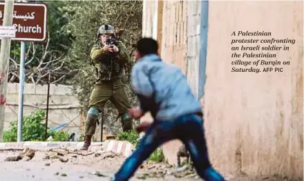  ?? AFP PIC ?? A Palestinia­n protester confrontin­g an Israeli soldier in the Palestinia­n village of Burqin on Saturday.