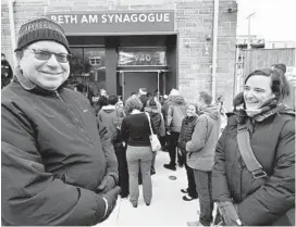  ??  ?? Beth Am congregant­s Daniel Appleby, left, a member of five years, and Amy Nathanson, right, a lifelong member, gathered on Eutaw Place with others for the mezuza ceremony Sunday to mark the completion of a major renovation at the Reservoir Hill synagogue.
