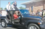  ?? Westside Eagle Observer/SUSAN HOLLAND ?? Homecoming queen candidate Madison McDaniel prepares to throw a piece of candy to a spectator as she rides down Main Street in the football homecoming parade. Madison was crowned homecoming queen in ceremonies at the football field Friday evening before the game with the Lincoln Wolves.