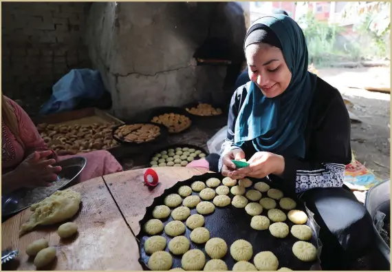  ??  ?? A woman prepares ‘kahk’, Egyptian butter cookies, in the village of Dalgamon, about 120 kilometres north of Cairo, as people prepare to mark Eid Al Fitr
