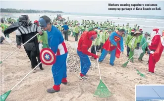  ??  ?? Workers wearing superhero costumes sweep up garbage at Kuta Beach on Bali.