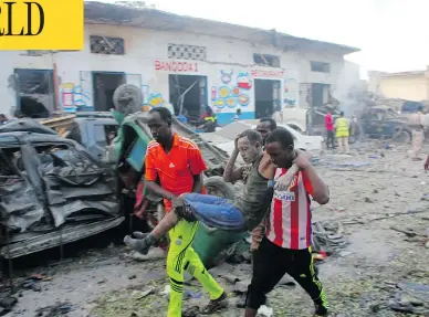  ?? FARAH ABDI WARSAMEH / THE ASSOCIATED PRESS ?? Somalis carry away a man injured by a car bomb at a hotel in Mogadishu, Somalia on Saturday. The attack, which killed 23, as well as one two weeks ago that killed 350 on a city street, has shaken public confidence in the military.