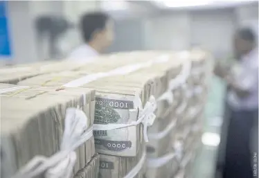  ??  ?? Stacks of kyat banknotes are piled on the counter at a bank in Yangon.