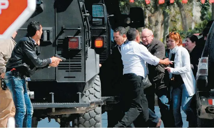  ??  ?? Sous la surveillan­ce des policiers armés jusqu’aux dents, des touristes ont été escortés à l’extérieur du musée du Bardo en plein coeur de Tunis où a eu lieu la fusillade, hier.