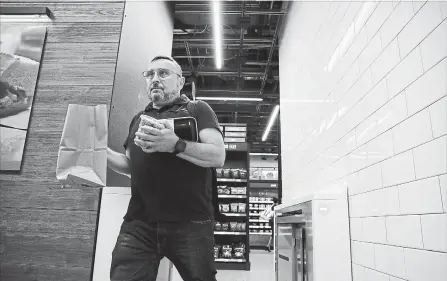  ?? STACEY WESCOTT TNS ?? Peter Feldman walks out with his purchases from a cashierles­s Amazon Go store in Chicago. It wants to add another 3,000 of the stores by 2021.