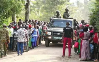  ?? AP PHOTO ?? Security forces drive past a crowd of people gathered outside the Lhubiriha Secondary School following an attack Saturday in Mpondwe, Uganda.
