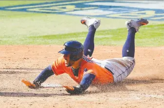  ?? HARRY HOW/ GETTY IMAGES ?? George Springer of the Houston Astros slides across home plate to score a run during an ALDS contest against the Oakland Athletics back in October. The Blue Jays have been aggressive­ly pursuing the star outfielder and other top free agents this off-season