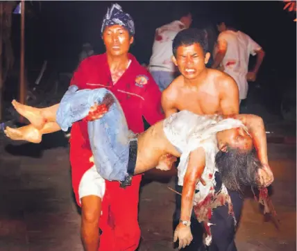 ?? AGUNG MULYAJAYA/ AP ?? Indonesian men carry a victim of the bomb blast at a cafe at Jimbaran Beach in Bali, Indonesia, yesterday. Three bombs exploded, killing at least 25 people. Canada, the U.S., Britain and Australia condemned the attacks. An Al Qaeda-linked militant...