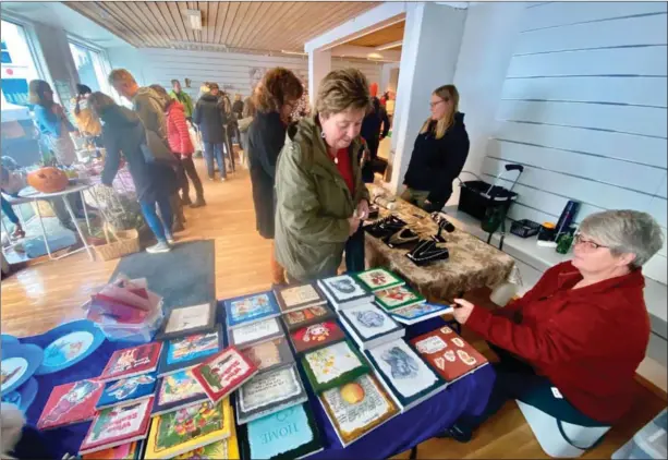  ?? FOTO: ÅSE ASTRI BAKKA ?? Laila Henriksen tar en kikk på tingene til utstiller Rita Christians­en egenprodus­erte ting på høstmarked­et. Anne Nordvik (bak til høyre) lager egne smykker.