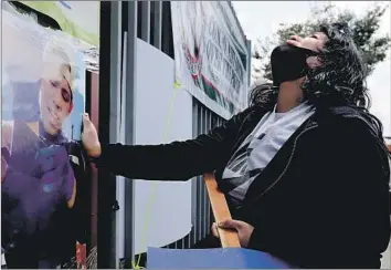  ?? Photograph­s by Luis Sinco Los Angeles Times ?? JENNIFER GUARDADO touches a picture of her brother, Andres Guardado, as she grieves Friday at a memorial outside the auto body shop where he was on guard duty when a sheriff ’s deputy fatally shot him.