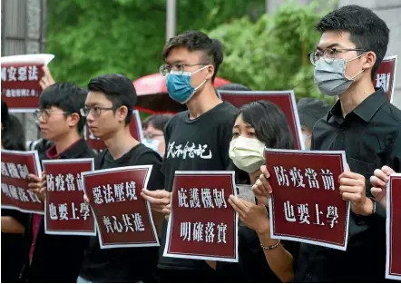  ?? AP ?? Hong Kong students and Taiwanese supporters hold slogans reading: ‘‘Evil law under the pressure of the border, Work hand in hand ‘‘ and ‘‘The asylum mechanism is clearly in place’’ during a protest against Beijing’s national security legislatio­n in Taipei this week.