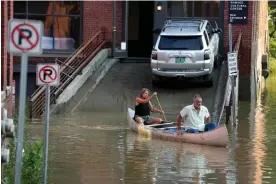  ?? Photograph: Steven Senne/AP ?? A married couple use a canoe to remove surgical supplies from a flood-damaged veterinary center in Montpelier, Vermont, on 11 July 2023.